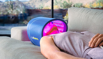 Woman laying on couch under a Celluma PRO receiving a facial treatment with red light therapy to address aging skin and wrinkles