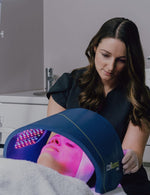 Aesthetician using a Celluma Pro light therapy device on client's face